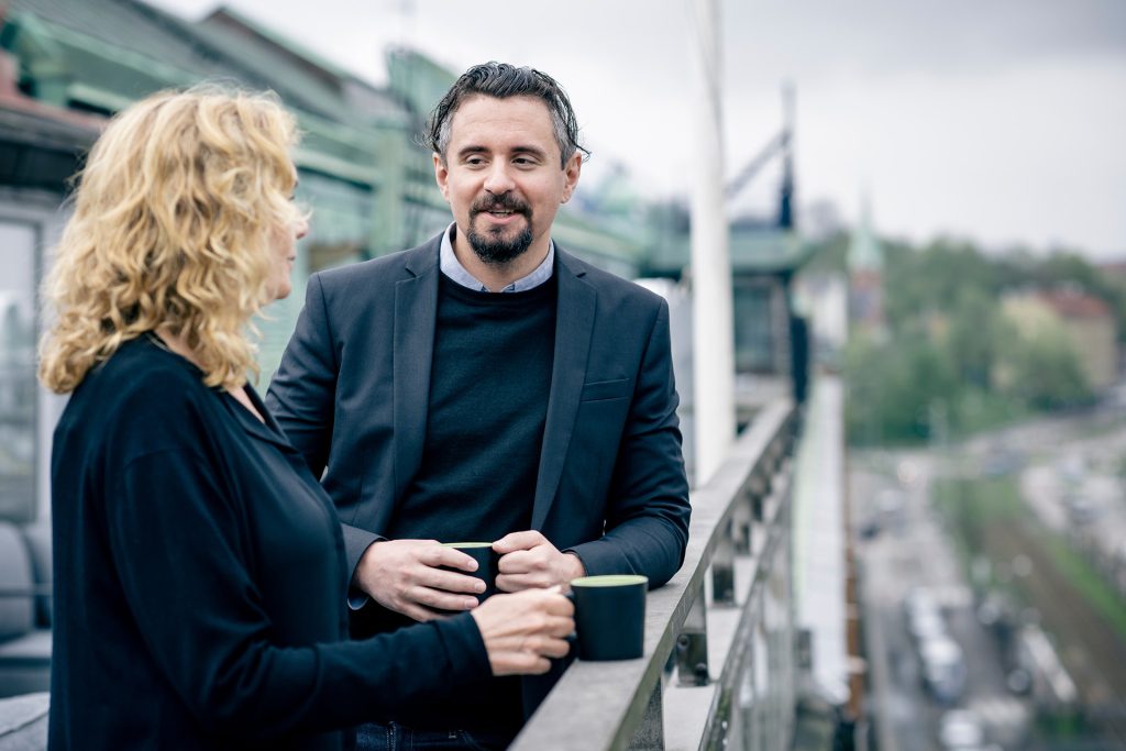 Två av Didups medarbetare står på takterassen och pratar med varandra med varsin kopp kaffe.